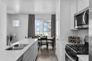 Kitchen featuring stainless steel microwave, gas range, healthy amount of natural light, light wood-style flooring, and recessed lighting