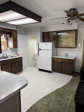 Kitchen featuring freestanding refrigerator, ceiling fan, light countertops, dark brown cabinetry, and a textured ceiling