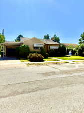 Single story home featuring concrete driveway, a carport, a chimney, a front yard, and brick siding