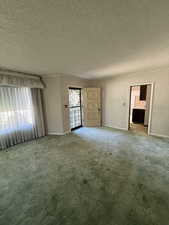 Unfurnished living room with a textured ceiling and carpet floors