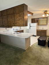 Kitchen with freestanding refrigerator, a textured ceiling, ceiling fan, a peninsula, and light countertops