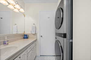 Bathroom with stacked washer and clothes dryer, vanity, and tile patterned floors