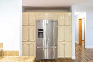 Kitchen featuring stainless steel refrigerator with ice dispenser, cream cabinetry, and dark wood finished floors