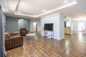 Living room featuring a tray ceiling, wood finished floors, and recessed lighting