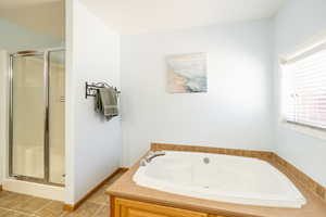 Full bath featuring a stall shower, a garden tub, and tile patterned floors