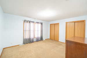 Unfurnished bedroom featuring light carpet and two closets