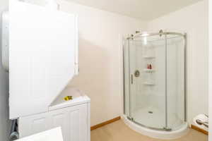 Bathroom featuring stacked washer / dryer and a shower stall