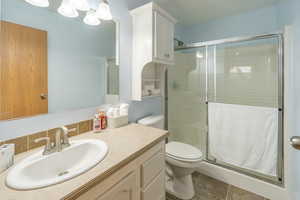 Bathroom with a shower stall, tile patterned flooring, and vanity