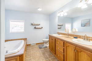 Full bathroom with double vanity, healthy amount of natural light, tile patterned floors, and a garden tub