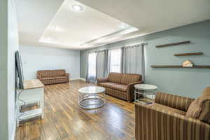 Living area with a tray ceiling, hardwood / wood-style floors, and recessed lighting