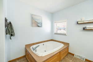 Full bathroom with a tub with jets and tile patterned flooring