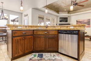 Kitchen featuring dishwasher, a tray ceiling, hanging light fixtures, and ceiling fan