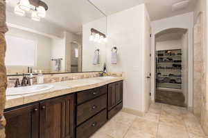 Full bathroom featuring double vanity, a spacious closet, and tile patterned flooring