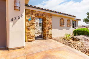 View of exterior entry with stone siding, stucco siding, and a tile roof