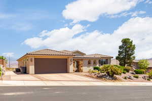 Mediterranean / spanish-style home featuring stucco siding, an attached garage, a tiled roof, and driveway