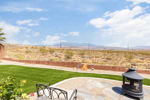View of grassy yard featuring a mountain view and a patio