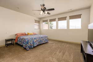 Carpeted bedroom featuring baseboards and ceiling fan