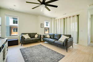 Living room with healthy amount of natural light, light wood-style floors, and ceiling fan