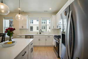 Kitchen featuring appliances with stainless steel finishes, white cabinets, healthy amount of natural light, recessed lighting, and pendant lighting