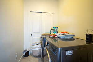 Laundry room featuring washer and clothes dryer and light tile patterned flooring