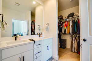 Bathroom with double vanity, wood finished floors, a walk in closet, and recessed lighting