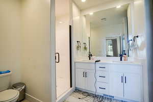 Full bath with a shower stall, double vanity, and recessed lighting