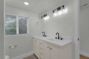 Full bathroom featuring a textured ceiling and double vanity