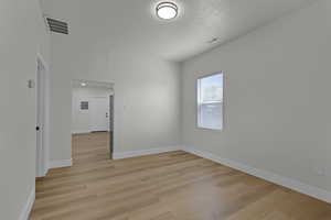 Spare room featuring light wood-type flooring and a textured ceiling