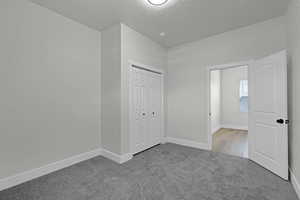 Unfurnished bedroom featuring carpet flooring, a closet, and a textured ceiling