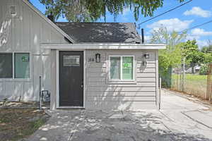 Doorway to property featuring board and batten siding and roof with shingles