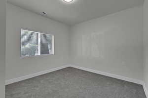 Unfurnished room featuring dark carpet and a textured ceiling