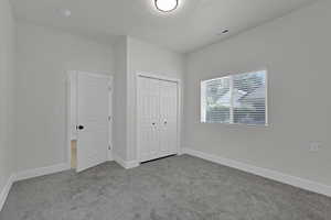 Unfurnished bedroom with carpet floors, a textured ceiling, and a closet
