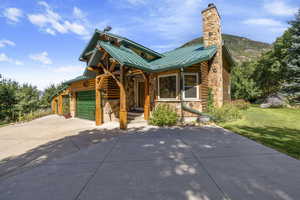Chalet / cabin with stone siding, an attached garage, a metal roof, a standing seam roof, and a chimney