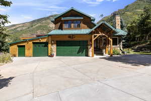 View of front of house with a mountain view, a chimney, concrete driveway, and an attached garage