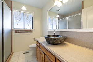 Full bath with tile patterned flooring, a stall shower, and vanity