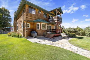 Rear view of property featuring a balcony, a patio, a yard, and a chimney