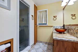 Full bathroom with a stall shower, vanity, and tile patterned flooring