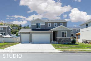 View of front of house featuring board and batten siding, driveway, an attached garage, and stone siding