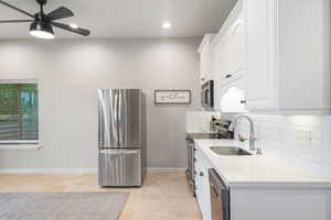 Kitchen featuring appliances with stainless steel finishes, white cabinetry, a ceiling fan, tasteful backsplash, and recessed lighting