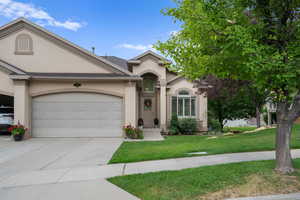 View of front of home featuring stucco siding, a garage, concrete driveway, and a front yard