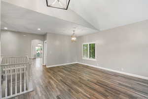Unfurnished room with arched walkways, a chandelier, dark wood-style floors, lofted ceiling, and recessed lighting