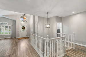 Entryway with a chandelier, wood finished floors, recessed lighting, and vaulted ceiling