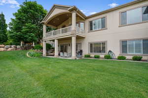 Rear view of property featuring a balcony, stucco siding, a patio area, and a yard