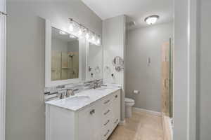 Bathroom with a shower stall, double vanity, tasteful backsplash, and tile patterned floors