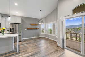 Kitchen with stainless steel fridge with ice dispenser, wood finished floors, light countertops, a chandelier, and hanging light fixtures