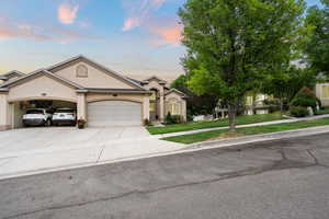Ranch-style house featuring stucco siding, a garage, driveway, and a lawn