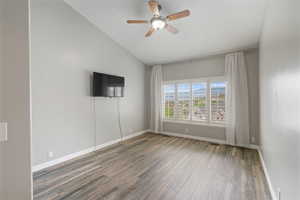 Empty room with lofted ceiling, wood finished floors, and a ceiling fan