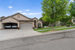 View of front of house featuring stucco siding, a garage, driveway, and a front yard