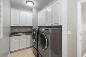 Laundry area featuring washer and clothes dryer, cabinet space, and light tile patterned floors