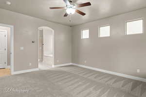 Spare room with arched walkways, light carpet, ceiling fan, and a smoke detector